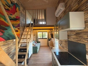 A compact kitchen with a built-in stove, a wooden staircase, and a colorful mural on the wall. - Chalet with garden and terrace in Saint-Xandre (Saint-Xandre)