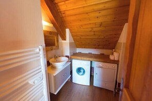 Cocina compacta con lavabo, lavadora y encimera de madera.