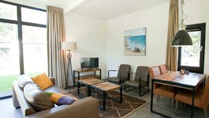 Een moderne woonkamer met een bank, salontafel, televisie en een eethoek.
