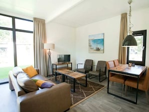 A modern living room with a sofa, coffee table, TV, and dining area. - Holiday Home in Otterlo With Terrace (Otterlo)