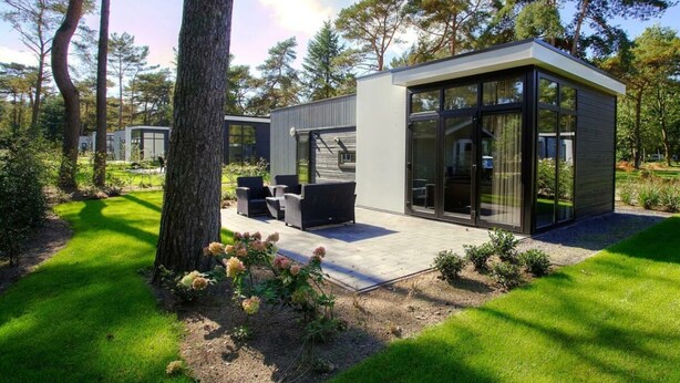 Een modern huis met een terras, buitenmeubels en een glazen deur.