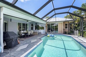 Une piscine extérieure couverte, dotée d’un patio, d’un barbecue et offrant une vue sur le paysage environnant.