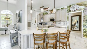 A spacious kitchen with a large island, pendant lights, and a ceiling fan. - Private Pool, Wifi, Outdoor Lounger, Family Fun (Rotonda West)