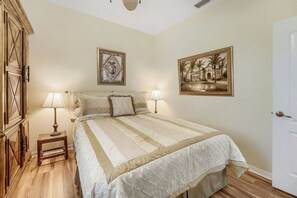 Ein Schlafzimmer mit einem Bett, zwei Nachttischlampen, einem Nachttisch und einem Kleiderschrank sowie zwei gerahmten Bildern an der Wand.