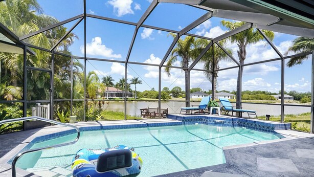 A pool with a clear view of the surrounding landscape, including palm trees and a body of water. - Private Pool, Wifi, Outdoor Lounger, Family Fun (Rotonda West)