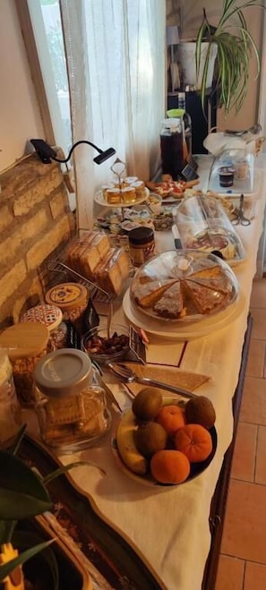 Een buffet met verschillende soorten eten, zoals fruit, gebak en sauzen.