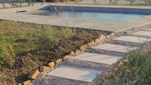 Un camino que lleva a una zona de piscina, con vegetación circundante y cielo despejado.