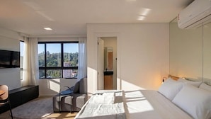 A modern hotel room with a large bed, a desk, a chair, and a TV. - Studio in Condo w/ Pool in Blumenau Pin1911 (Blumenau)