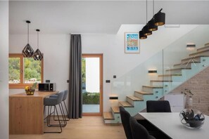 A modern kitchen with a wooden island, bar stools, and pendant lighting. - Villa Luka (Srima)