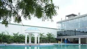 A swimming pool with a gazebo, a modern building, and a covered area with a slide. - Firefox Hotel and Resorts (Hyderabad)