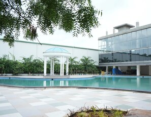 Una piscina con un pabellón, un edificio moderno y una zona cubierta con un tobogán.