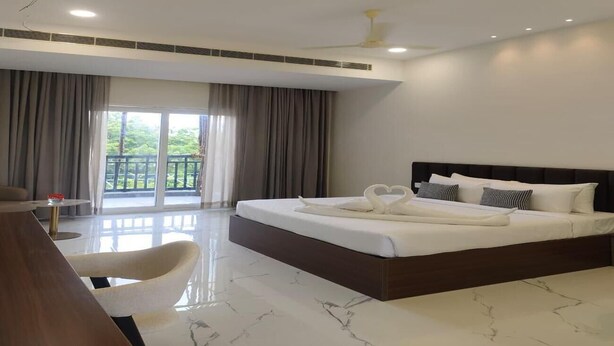 Habitación de hotel con cama, escritorio, silla y vistas al exterior.