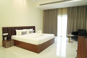 Una habitación de hotel con una cama grande, una mesita de noche, una silla y un escritorio.