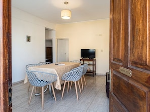 Un comedor con una mesa, sillas, un televisor y una puerta de madera con una etiqueta.