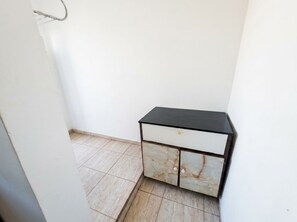 Una habitación de esquina con un mueble negro y blanco, una pared blanca y un suelo de baldosas.