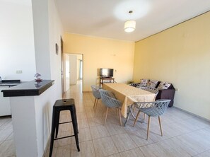 Un espace de vie compact comprenant un coin cuisine, une table à manger et un espace détente.
