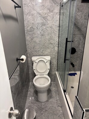 Ein Badezimmer mit Toilette, Duschkabine und Marmorboden.