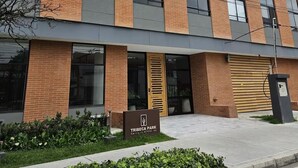 Um edifício moderno com fachada de tijolos, janelas grandes e uma placa com o nome Tribeca Park.