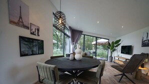 A modern dining area with a round table, chairs, and a hanging light fixture. - Pavilion Maximaal 4 (Kaatsheuvel)