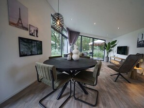 A modern dining area with a round table, chairs, and a hanging light fixture. - Pavilion Maximaal 4 (Kaatsheuvel)