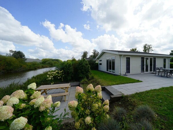 Ein Haus mit Terrasse, Fluss und Hortensienbüschen.