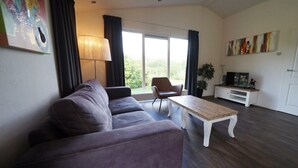 Ett modernt vardagsrum med en soffa, ett soffbord, ett TV-bord och en fåtölj.