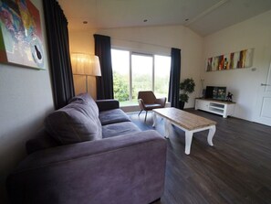 Ein modernes Wohnzimmer mit einer Couch, einem Couchtisch, einem TV-Schrank und einem Sessel.