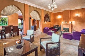 A spacious lobby with a fireplace, seating areas, and a dining setup. - Luxury Villa Riad & Serene ~ Pool ~ Spa! (Marrakesh)