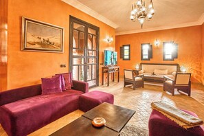 A living room with a sofa, coffee table, and a TV. - Luxury Villa Riad & Serene ~ Pool ~ Spa! (Marrakesh)
