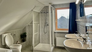 Ein modernes Badezimmer mit Dusche, Toilette und zwei Waschbecken.