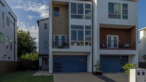 A modern multi-story residential building with a garage, a balcony, and a well-maintained lawn. - Dallas Luxury Smart Home Near Golf, Trails, Tennis, Shopping & Downtown Access (Dallas)