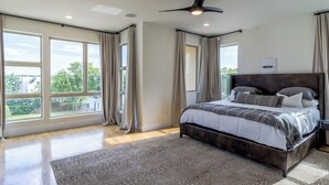 A bedroom with a large bed, a ceiling fan, and multiple windows. - Dallas Luxury Smart Home Near Golf, Trails, Tennis, Shopping & Downtown Access (Dallas)