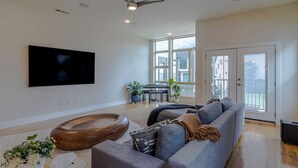 A spacious living room with a large flat-screen TV, a ceiling fan, and a piano. - Dallas Luxury Smart Home Near Golf, Trails, Tennis, Shopping & Downtown Access (Dallas)