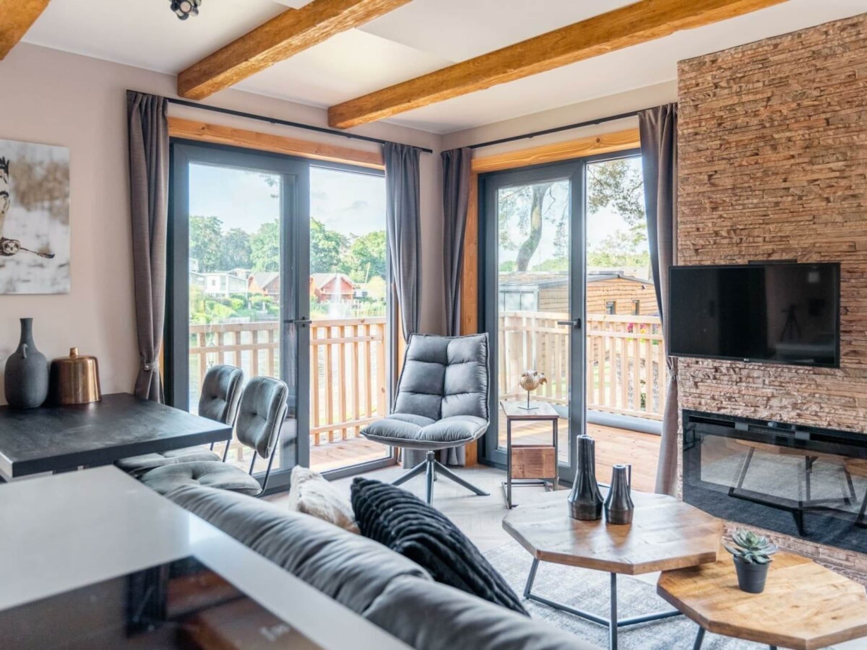 Ein modernes Wohnzimmer mit Sofa, Sesseln, Couchtisch und Fernseher, der an einer Ziegelwand angebracht ist.