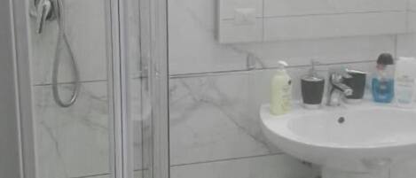 A bathroom with a glass shower enclosure, a white sink, and a mirror above it.