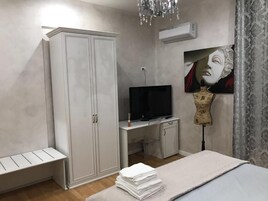 Un dormitorio con armario, escritorio con televisor, un maniquí y una cama.