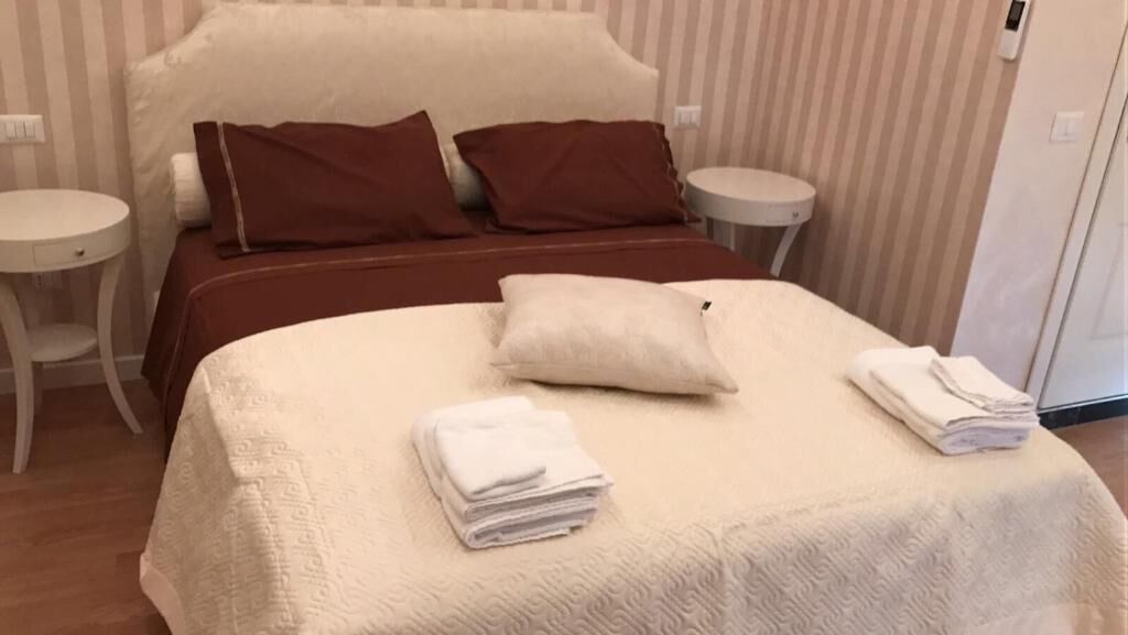 Un lit bien fait, avec une couette blanche, deux oreillers marron et des serviettes blanches pliées.