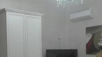 Un dormitorio con cama, televisión, armario y candelabro.