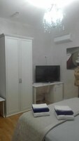 Un dormitorio con cama, televisión, armario y candelabro.