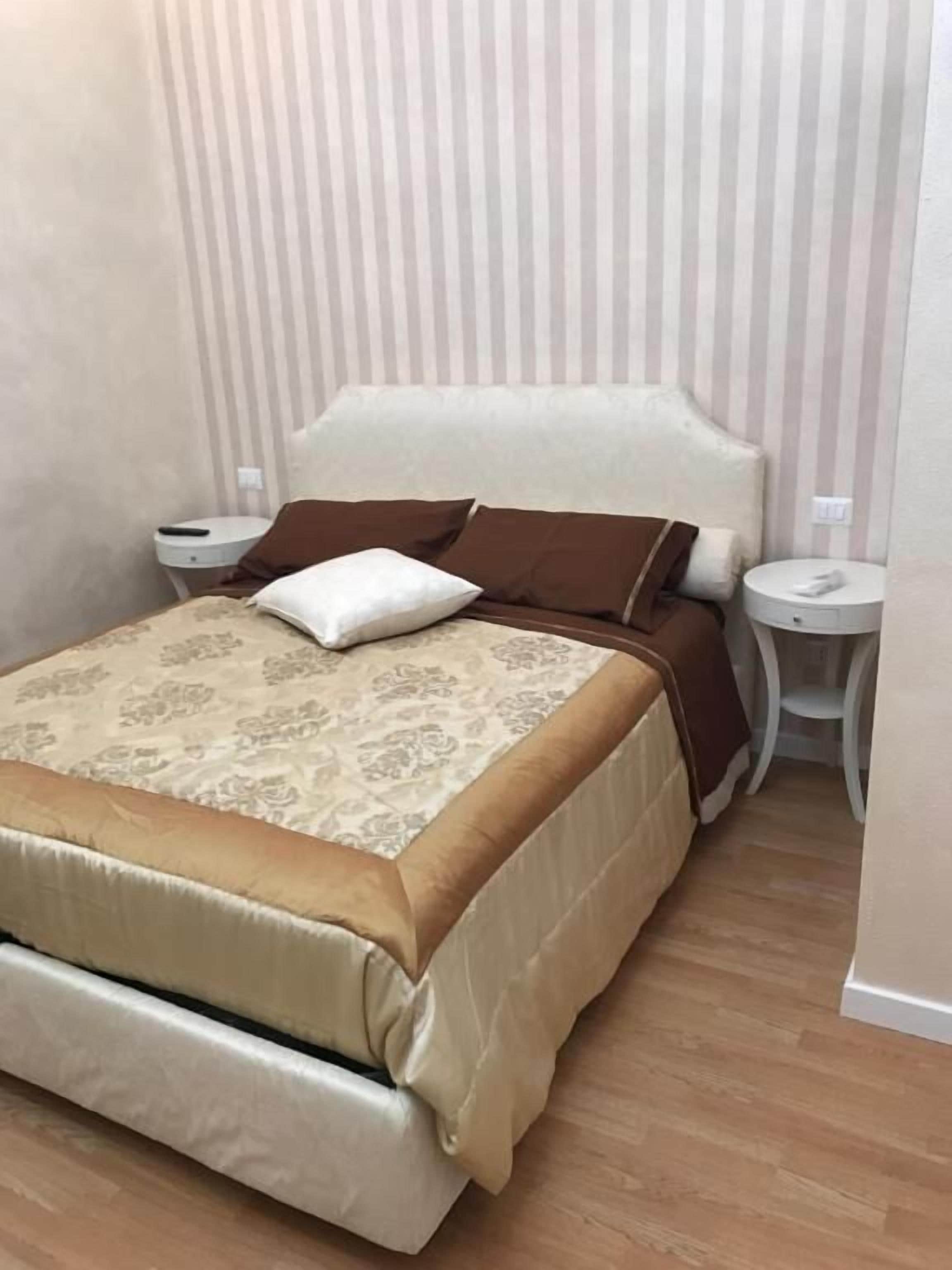 A bed with a headboard, two bedside tables, and a patterned bedspread.