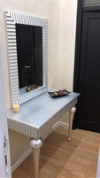 Un tocador con espejo y un cuenco sobre una mesa.