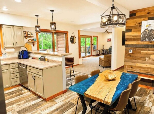A modern kitchen with a central island, wooden flooring, and a dining area with a table and chairs.
