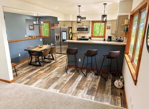 Una cocina moderna con taburetes de bar, una mesa de comedor y una isla grande.