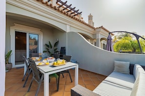 Eine Terrasse mit Esstisch, Stühlen, einer Couch und einem Topfpflanzen.