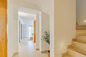 Ein modernes Interieur mit einer Treppe, einem Flur, der zu einem anderen Raum führt, und einem Blumentopf.