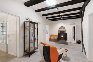Ein modernes Interieur mit freiliegenden Balken, einem Kamin und einer Glastrennwand.