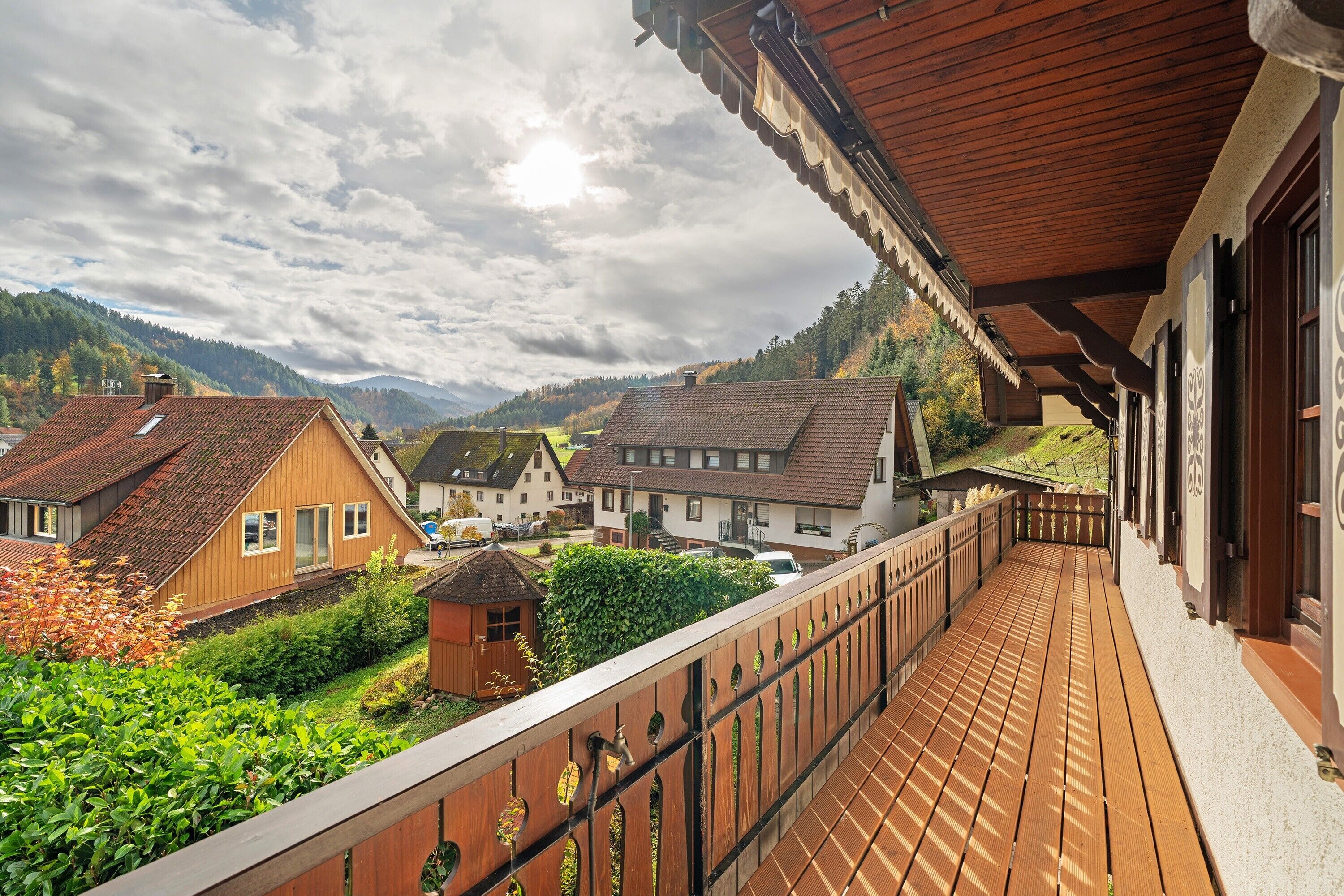 Un balcon en bois offrant une vue sur les maisons et les montagnes.