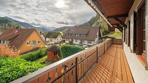 A wooden balcony with a view of houses and mountains. - Apartment 'Ferienwohnung Höflelounge' with Mountain View, Balcony and Wi-Fi (Oppenau)