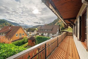 Ein Holzbalkon mit Blick auf Häuser und Berge.