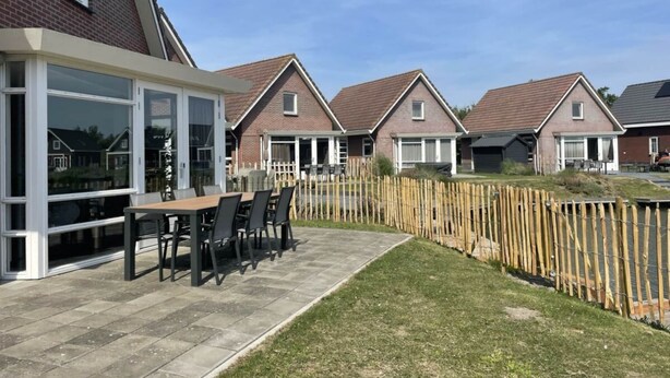 Ein Wohngebiet mit Häusern, einer Terrasse mit Tisch und Stühlen und einem Holzzaun.